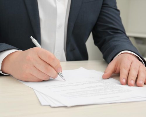 Homme signant un document à une table en bois, gros plan